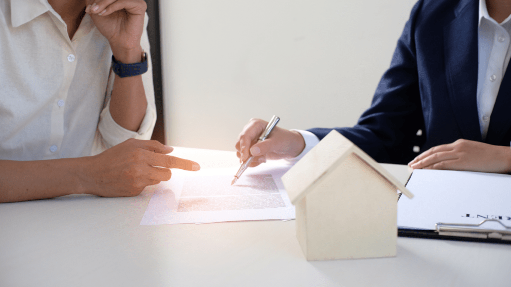 two people sitting at a table with a house model in front of them