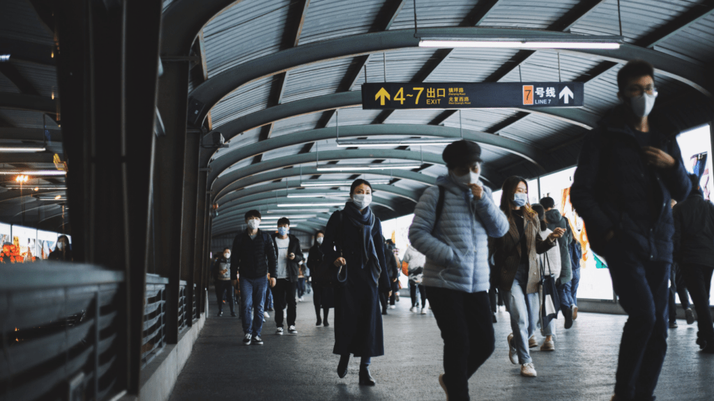 People wearing face masks walk through a subway station