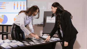 two individuals in business attire looking at papers on a table