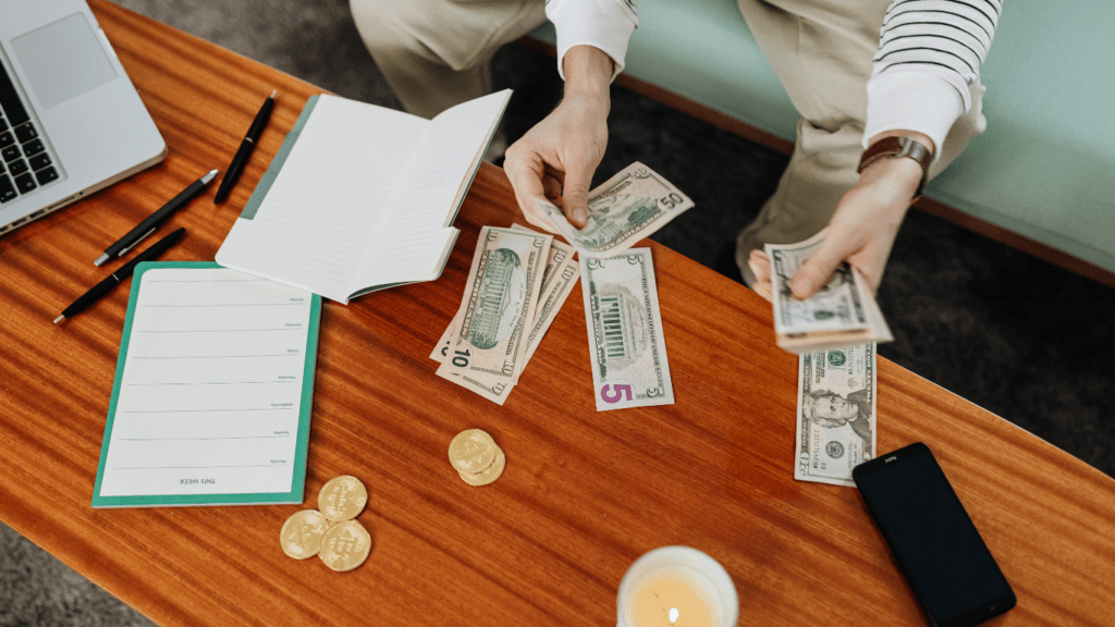 a person is holding money in front of a laptop